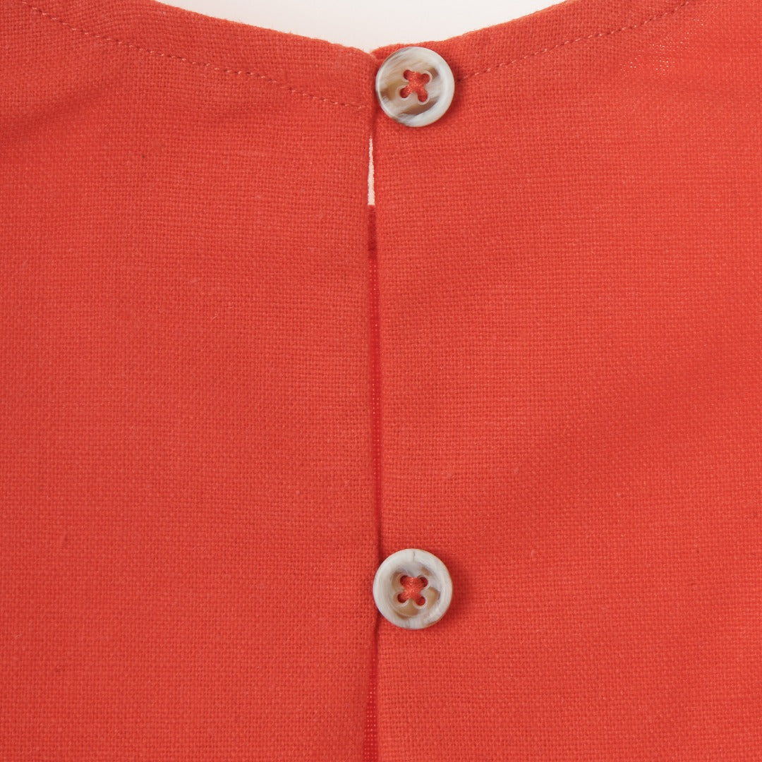 Red sleeveless blouse, fancy large bow. Back fastened by two buttons. 