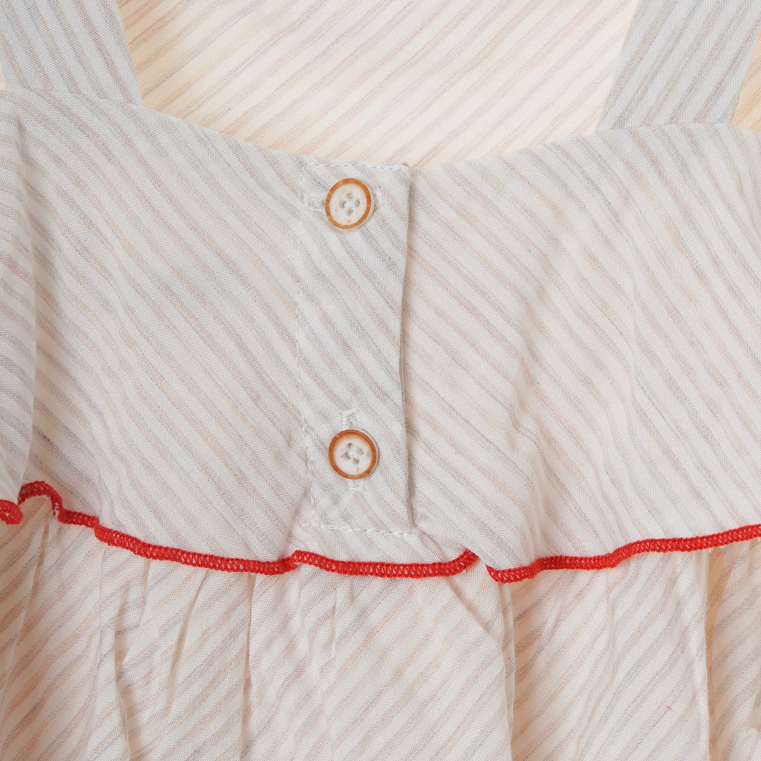 A Multi-layered and ruffled spaghetti strap blouse with red highlights buttoned at the front. 